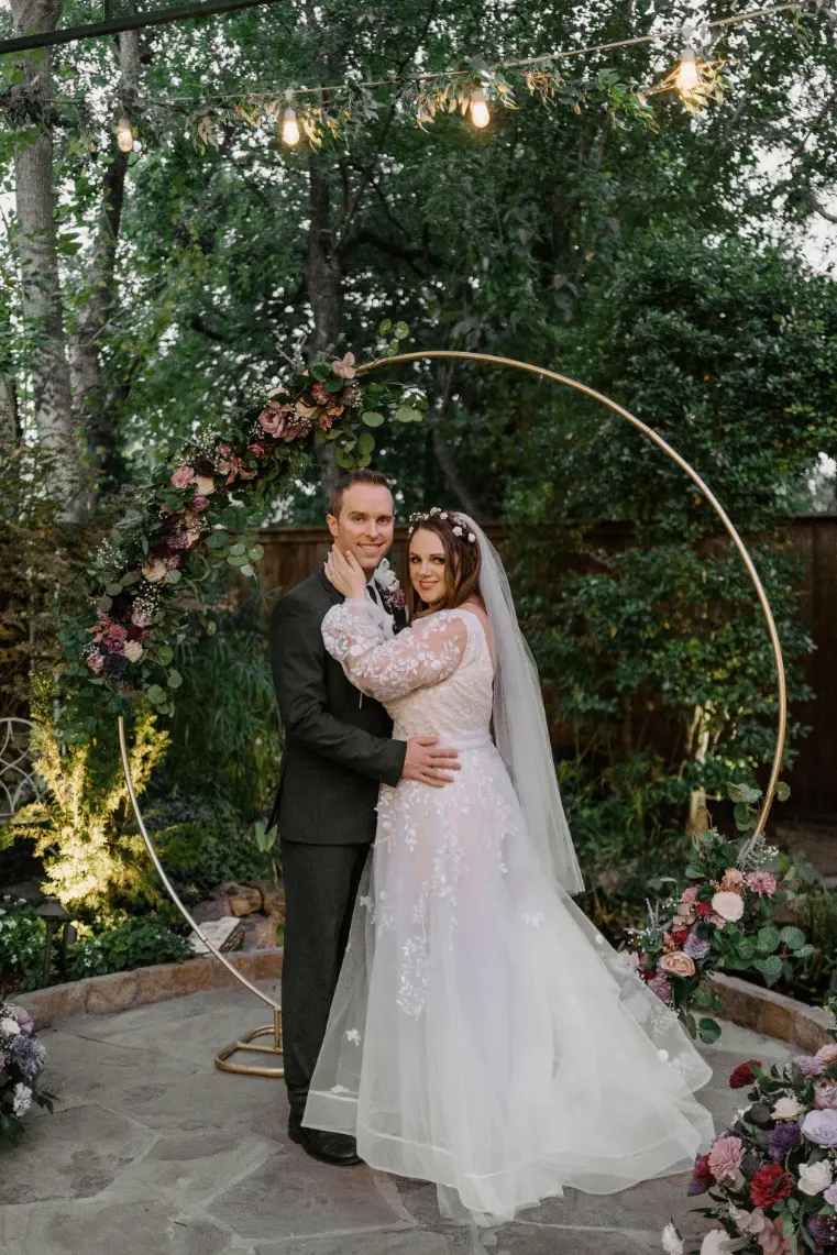 Wedding couple posing under the circular arch with a gorgeous greenery backdrop